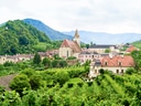 Malerische Landschaft mit Dorf und Kirche in hügeliger Umgebung.