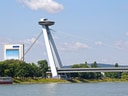 Brücke mit Aussichtsturm über Fluss unter blauem Himmel.