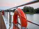 Rettungsring an Schiffsreling bei Sonnenuntergang.