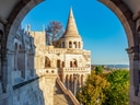 Historische Burg mit Treppen und Bäumen im Hintergrund.