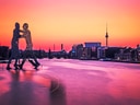 Skulptur und Berliner Skyline bei Sonnenuntergang.