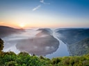 Landschaft mit Flussbiegung und Sonnenaufgang.