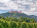 Grosses Kloster auf bewaldetem Hügel unter bewölktem Himmel.