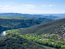 Landschaft mit Fluss, Hügeln und Bäumen im Tal.