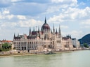 Ungarisches Parlamentsgebäude am Wasser mit Wolkenhimmel.