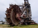 Grosser Bagger auf einer Wiese bei bewölktem Himmel.