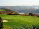 Golfspieler auf einem Platz mit Hügeln im Hintergrund.