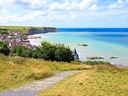 Pfad führt zu Küste mit Klippen, Dorf und Meer.