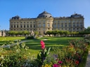 Grosses historisches Gebäude mit Garten und Blumen im Vordergrund.