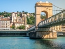 Brücke über einen Fluss in einer Stadt mit Hügeln und historischen Gebäuden.