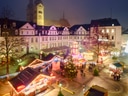 Weihnachtsmarkt auf einem historischen Platz mit beleuchteten Buden bei Nacht.