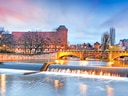 Fluss in Nürnberg mit beleuchtetem Brückenbogen und Gebäuden im Hintergrund.