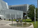 Moderne Architektur mit einer Skulptur aus silbernen Kugeln vor einem Gebäude.
