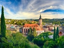 Panoramablick auf eine Stadt mit Kirche und umgebender Natur.