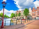 Kanal mit Brücke und traditionellen Gebäuden bei sonnigem Wetter.