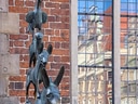 Bronzestatue der Bremer Stadtmusikanten vor Backsteinwand.