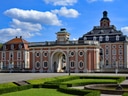 Barockschloss mit prachtvollen Gärten und blauem Himmel.