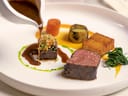 Gourmetgericht mit Fleisch, Gemüse und Sosse auf Teller.