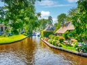 Landschaft mit Kanal, Bäumen und Häusern mit Strohdächern.