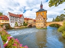Historisches Gebäude auf Brücke über Fluss in malerischer Stadt.