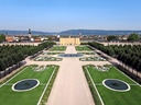 Schlosspark mit symmetrischen Gartenanlagen und Schloss im Hintergrund.