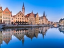 Historische Gebäude an einem Fluss mit klarer Spiegelung im Wasser.