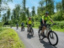 Gruppe von Radfahrern auf Waldweg bei sonnigem Wetter.