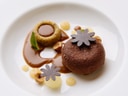 Schokoladendessert mit Sosse und Nüssen auf einem weissen Teller.