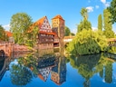 Malersiche Flusslandschaft mit Fachwerkhäusern und Brücken in einer Stadt.