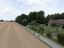 Gruppe von Radfahrern auf ländlicher Strasse neben Feld und Bauernhof.