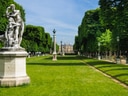 Skulpturen und Rasen in einem formalen Garten mit Bäumen.