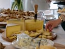 Tisch mit verschiedenen Käsesorten und Personen, die Käse servieren.