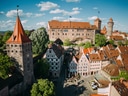 Luftbild einer mittelalterlichen Burg und Stadt mit roten Ziegeldächern.
