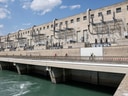 Grosses Gebäude mit technischen Strukturen neben einer Wasserstrasse.