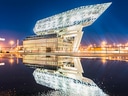Modernes Gebäude mit spiegelnder Wasseroberfläche bei Nacht.