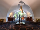 Skulptur in einer eleganten Hotellobby mit Lederstühlen und Bogenfenster.