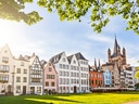 Bunte Häuserreihe und Kirche am sonnigen Tag.