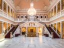 Grosse Halle mit Treppen und Kronleuchter, verziertem Interieur.