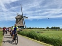 Radfahrer auf einem Weg neben einer Windmühle.