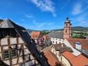 Blick auf historische Fachwerkhäuser und eine Kirche vor blauem Himmel.