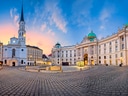 Historischer Platz mit Kirche und barocken Gebäuden bei Sonnenuntergang.