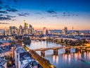 Skyline von Frankfurt bei Sonnenuntergang, Fluss im Vordergrund.