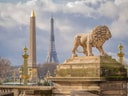 Löwenstatue mit Eiffelturm und Obelisk im Hintergrund.