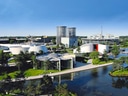 Moderne Gebäude und Landschaft bei Sonnenschein, mit Wasserflächen.