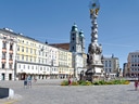 Historischer Platz mit Dreifaltigkeitssäule und farbigen Gebäuden.