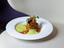 Gourmetgericht auf weissem Teller mit Schaum und Gemüsegarni.