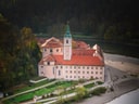Kloster mit reflektierendem Wasser im Herbst.
