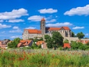 Historische Kirche und Häuser hinter Wildblumenwiese.