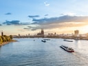 Panoramablick auf den Fluss Rhein mit Schiffen und Kölner Dom im Hintergrund.