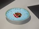 Ein kunstvoll angerichtetes Dessert auf einem blauen Teller.